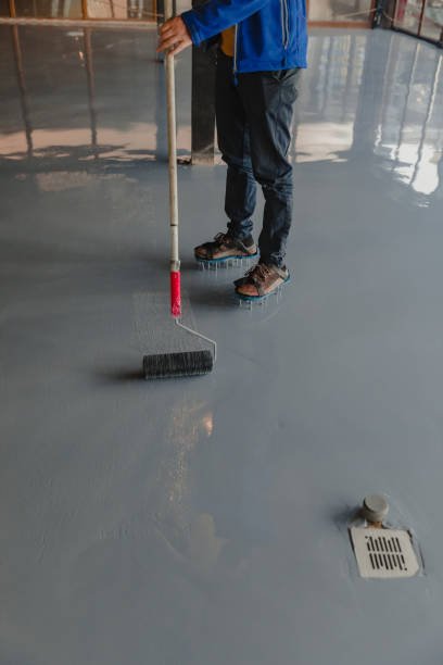 The worker applies gray epoxy resin to the new floor